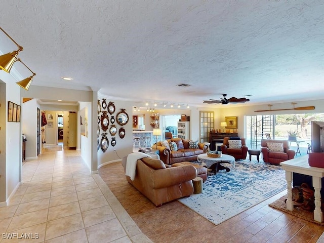 living room featuring light tile patterned floors, a textured ceiling, ornamental molding, and ceiling fan