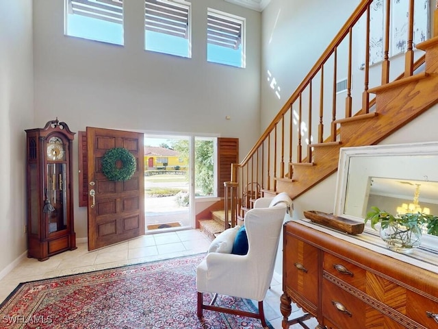 foyer entrance with light tile patterned flooring, an inviting chandelier, and a high ceiling