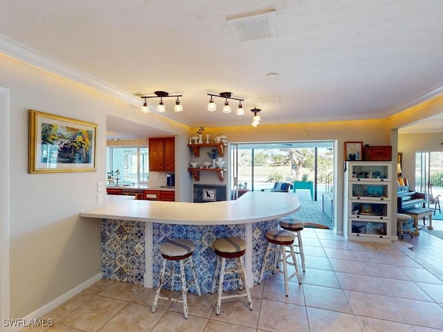 kitchen featuring light tile patterned floors, kitchen peninsula, a kitchen breakfast bar, and decorative backsplash