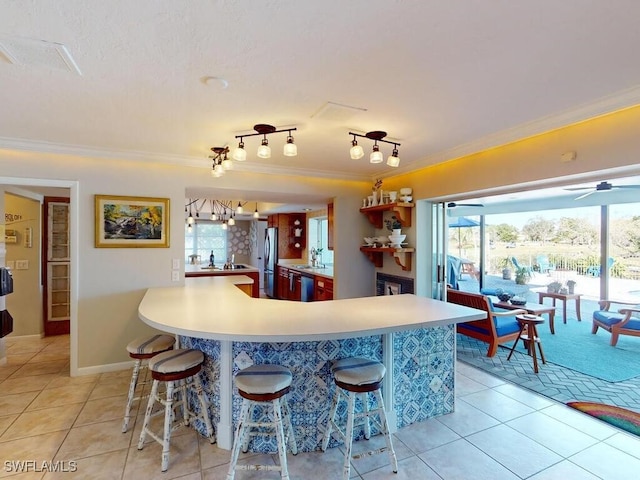 kitchen featuring sink, ornamental molding, a kitchen breakfast bar, and light tile patterned flooring