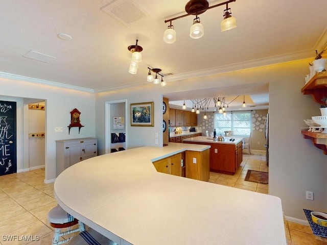 kitchen featuring crown molding, pendant lighting, light tile patterned floors, and kitchen peninsula