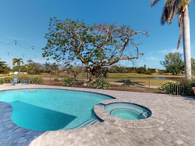 view of swimming pool with a patio, a water view, and an in ground hot tub