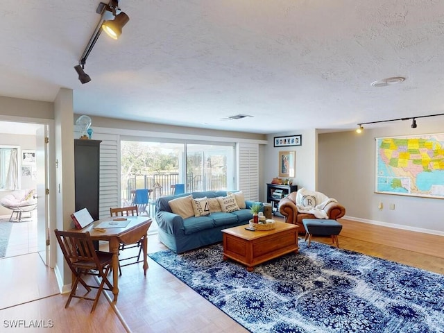 living room featuring rail lighting, a textured ceiling, and light wood-type flooring