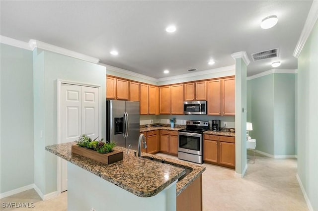 kitchen with stainless steel appliances, crown molding, and dark stone countertops