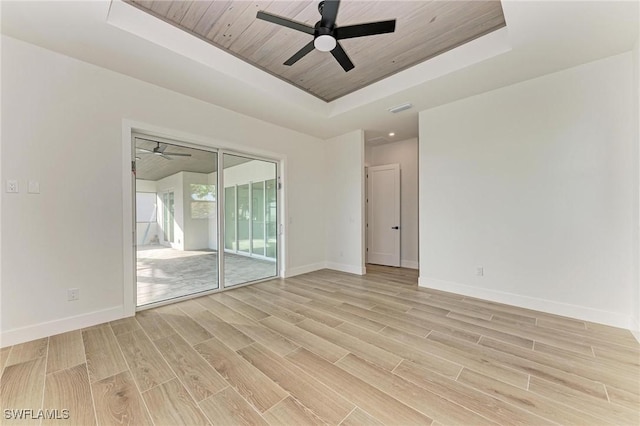 empty room featuring a tray ceiling, ceiling fan, light hardwood / wood-style flooring, and wooden ceiling