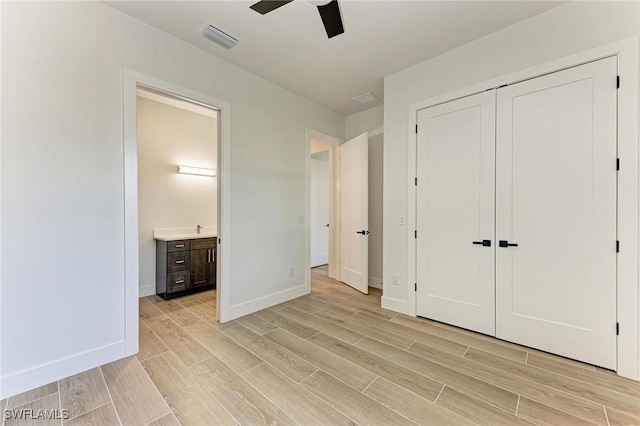 unfurnished bedroom featuring ensuite bath, ceiling fan, and a closet