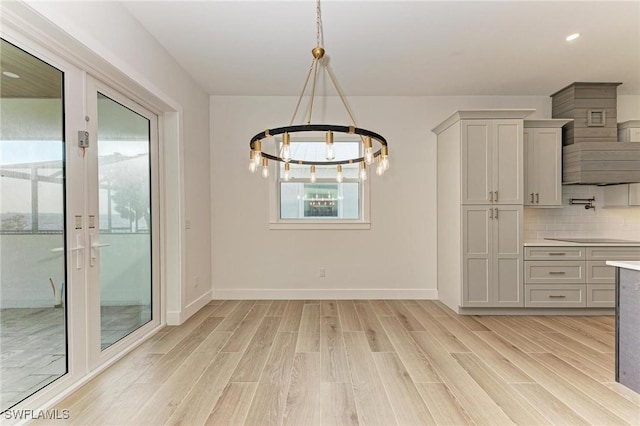 unfurnished dining area featuring light hardwood / wood-style flooring and a notable chandelier