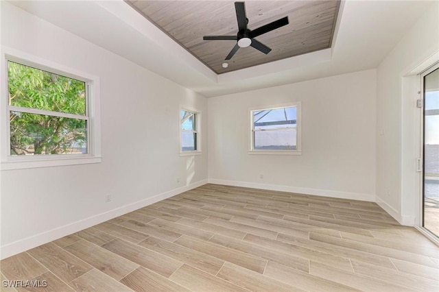 unfurnished room featuring ceiling fan, light hardwood / wood-style floors, wooden ceiling, and a tray ceiling