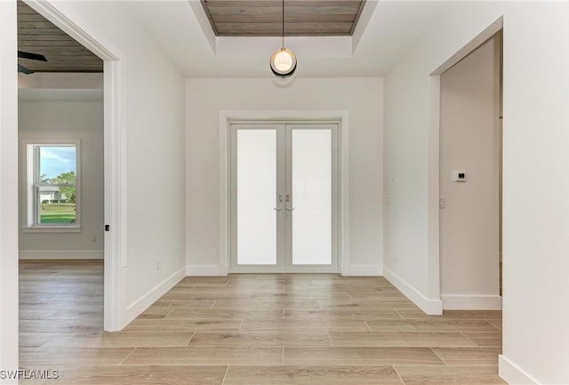 foyer with a raised ceiling, french doors, and light hardwood / wood-style flooring