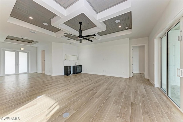 unfurnished living room featuring a tray ceiling, ceiling fan, french doors, and light hardwood / wood-style floors