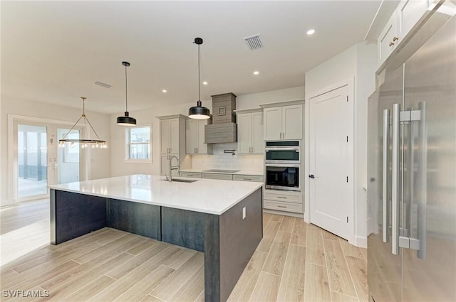 kitchen featuring appliances with stainless steel finishes, tasteful backsplash, a spacious island, sink, and decorative light fixtures