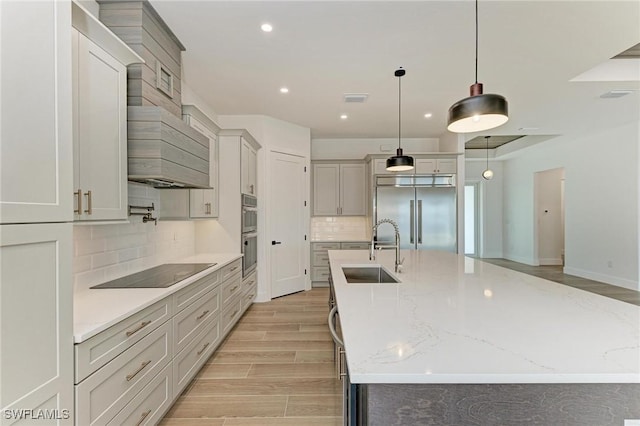 kitchen featuring a large island, stainless steel built in refrigerator, sink, and black electric cooktop