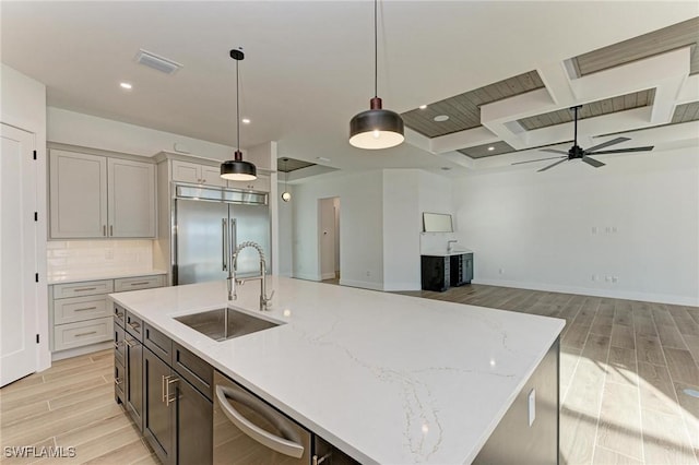 kitchen featuring sink, decorative backsplash, an island with sink, decorative light fixtures, and stainless steel appliances