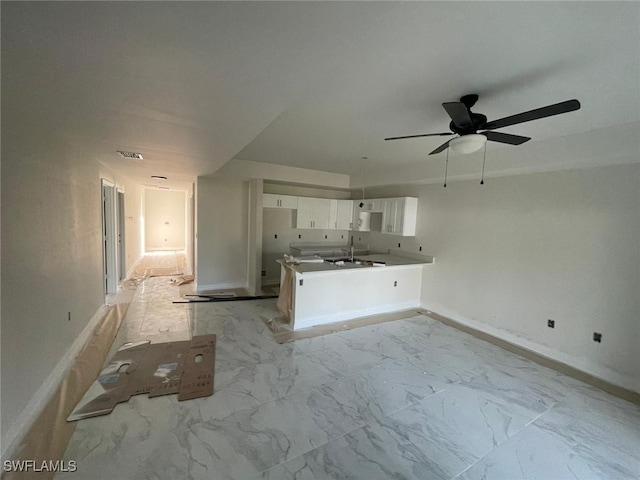 unfurnished living room featuring ceiling fan and sink