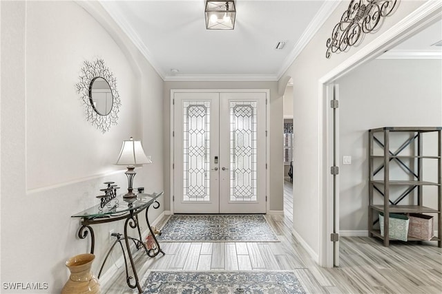 foyer entrance with light wood-type flooring, crown molding, a healthy amount of sunlight, and french doors