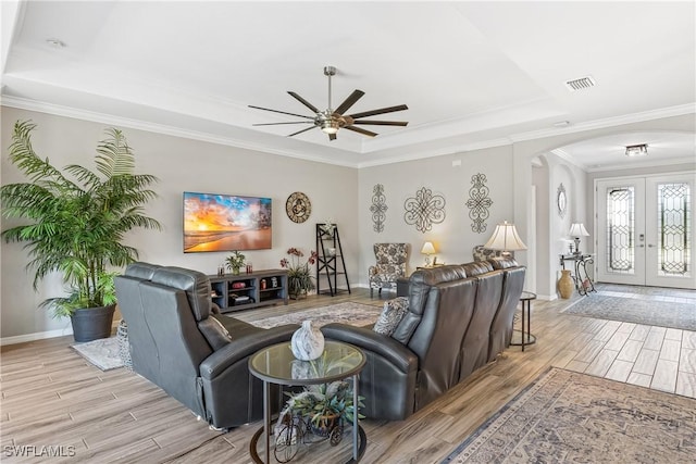 living room featuring ceiling fan, french doors, a tray ceiling, and ornamental molding