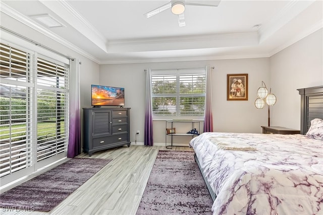 bedroom with ceiling fan, multiple windows, light hardwood / wood-style flooring, and a raised ceiling