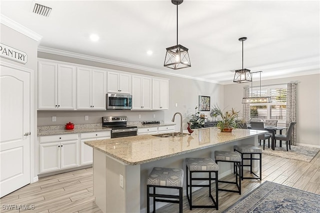 kitchen with white cabinetry, sink, stainless steel appliances, and a center island with sink