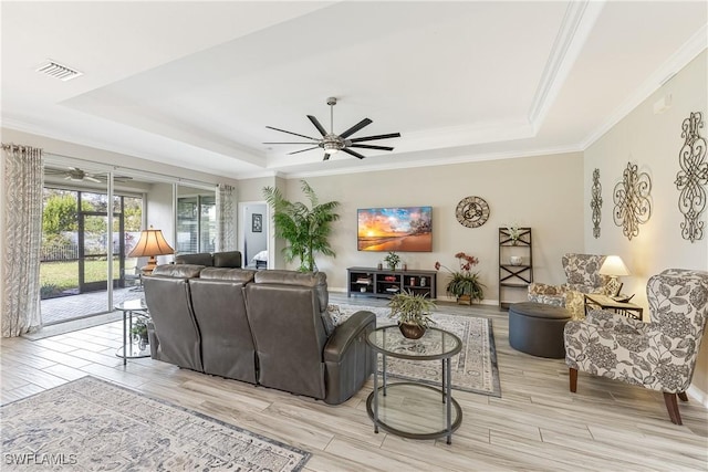 living room with ceiling fan, a tray ceiling, and crown molding