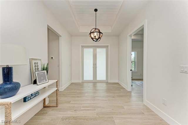 foyer entrance featuring a chandelier, french doors, and a raised ceiling