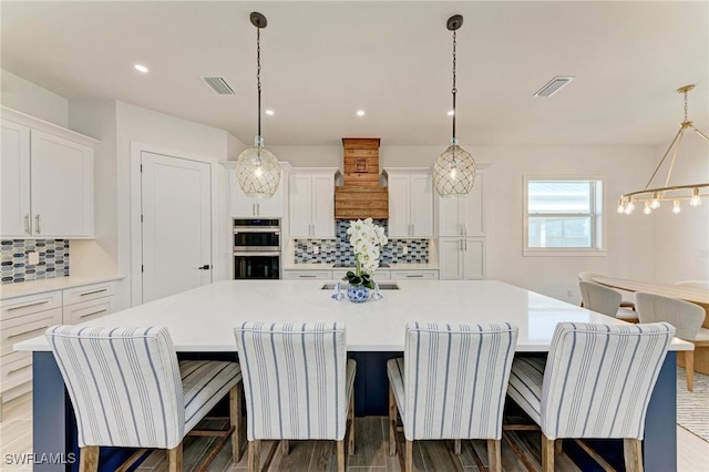 kitchen featuring white cabinetry, hanging light fixtures, and a large island