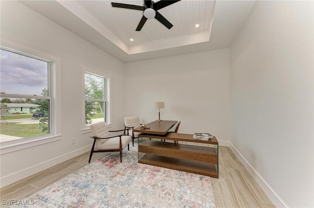 office with ceiling fan, a raised ceiling, and light hardwood / wood-style flooring