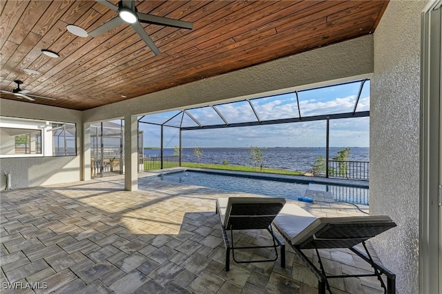 view of patio with a water view, glass enclosure, and ceiling fan