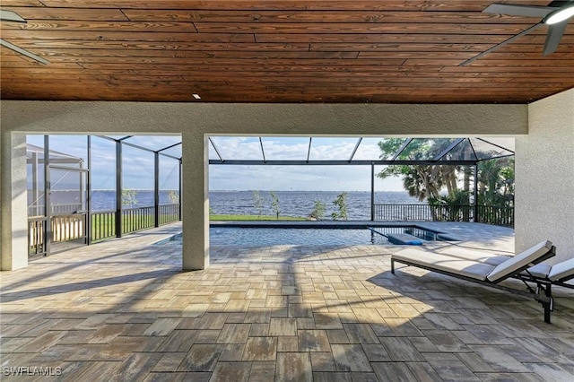 view of patio / terrace featuring a lanai, ceiling fan, and a water view