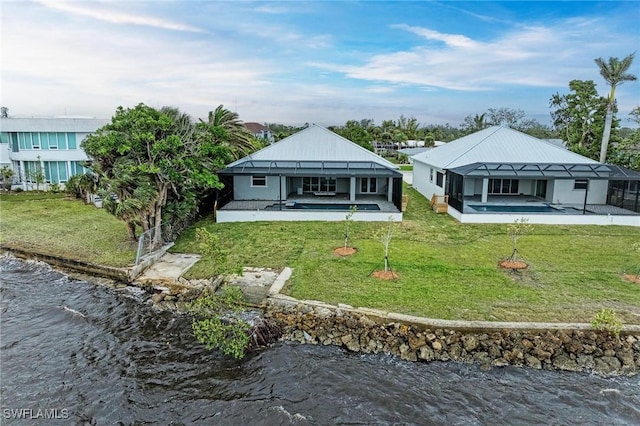 back of house featuring glass enclosure, a water view, and a patio