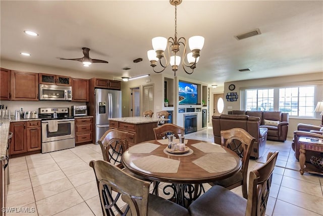 tiled dining area featuring ceiling fan with notable chandelier