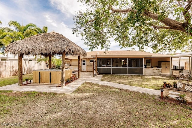 rear view of property featuring a sunroom, a patio, a hot tub, and area for grilling