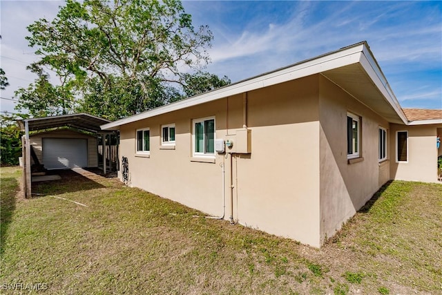 view of home's exterior with a yard, a carport, and an outbuilding