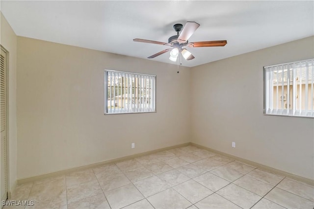 tiled empty room with ceiling fan and a wealth of natural light