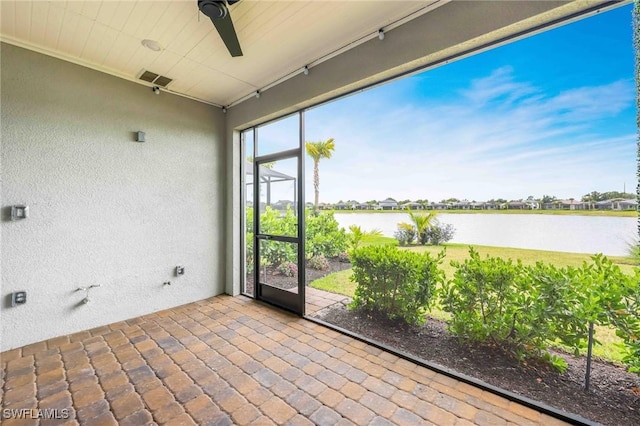 unfurnished sunroom with ceiling fan and a water view