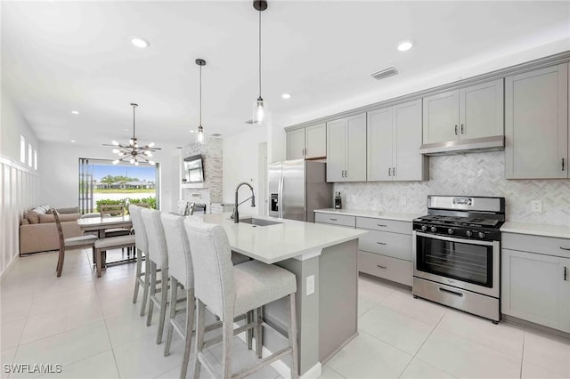 kitchen with gray cabinetry, pendant lighting, sink, an island with sink, and stainless steel appliances