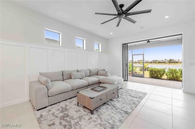 living room featuring a water view, ceiling fan, light tile patterned floors, and a healthy amount of sunlight