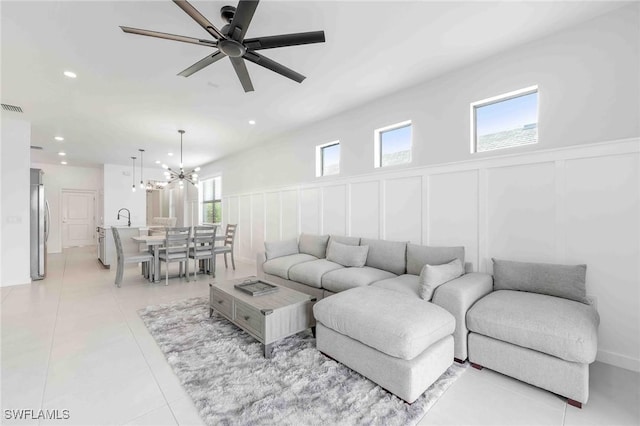 tiled living room featuring ceiling fan with notable chandelier and sink