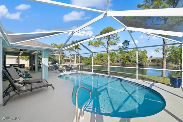 view of pool featuring a patio, a water view, and glass enclosure