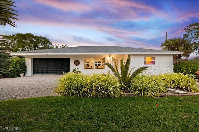 ranch-style house with a garage and a lawn