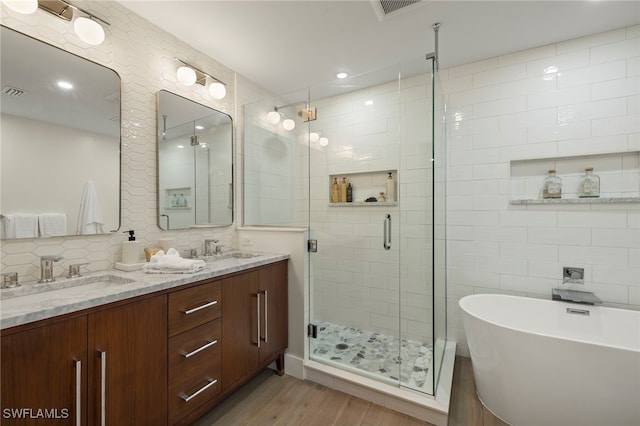 bathroom featuring vanity, plus walk in shower, hardwood / wood-style flooring, decorative backsplash, and tile walls