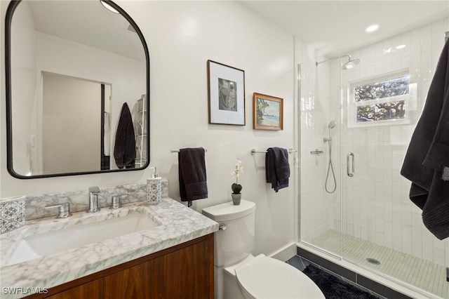 bathroom featuring vanity, toilet, and a shower with door