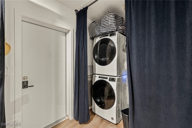 clothes washing area with light hardwood / wood-style floors and stacked washer and clothes dryer