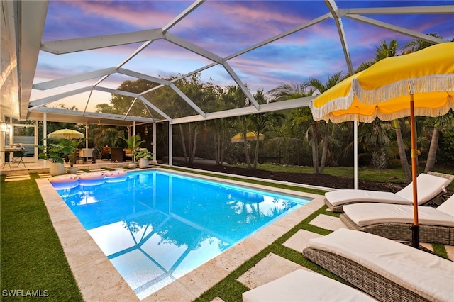 pool at dusk featuring a patio and glass enclosure