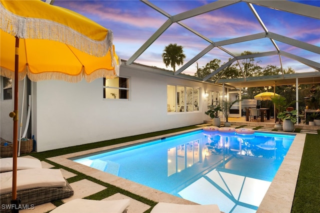 pool at dusk featuring a lanai and a patio area