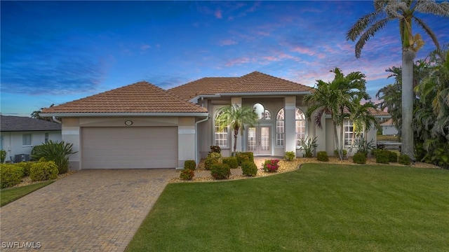 mediterranean / spanish-style house with french doors, a yard, and a garage