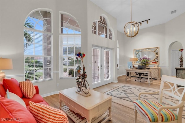 interior space with french doors, a notable chandelier, and light hardwood / wood-style flooring