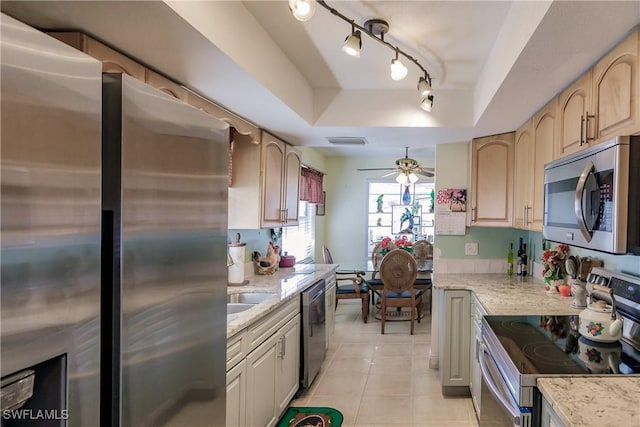 kitchen featuring light stone countertops, appliances with stainless steel finishes, a raised ceiling, ceiling fan, and light tile patterned floors