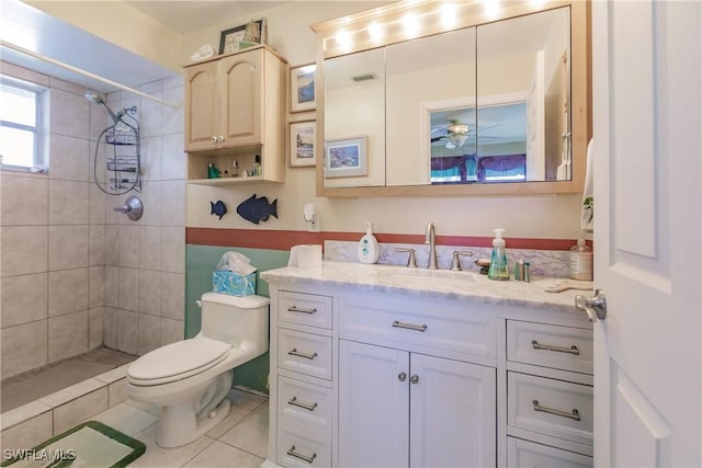 bathroom with toilet, a tile shower, vanity, and tile patterned floors