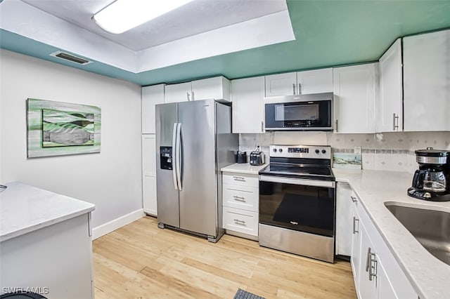 kitchen with tasteful backsplash, stainless steel appliances, sink, light hardwood / wood-style flooring, and white cabinetry