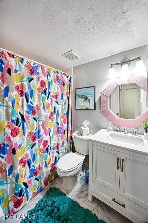 bathroom with vanity, toilet, and a textured ceiling